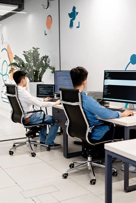 A photographer working at a creative setup with a laptop and Wacom tablet, focused on editing photos indoors.